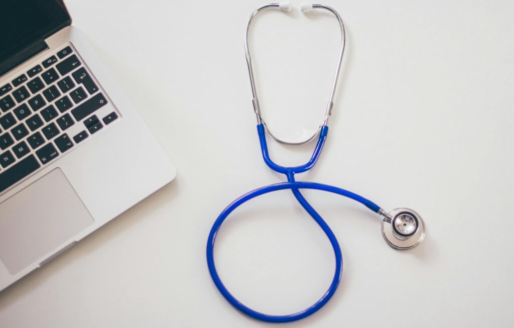zipwp image 48604 Medical stethoscope and laptop on a white desk, symbolizing digital health solutions.
